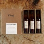 Coffret de trois bouteilles d'Armagnacs Darroze de la Collection Unique millésimes 2006, 1996 et 1986, portant l'étiquette « Les Flacons Darroze La Collection Unique », présenté sur un fond en bois.