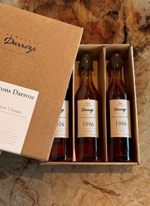 Coffret Les Flacons Darroze Collection Unique millésimes 2006, 1996 et 1986 posé sur du bois vue de haut.